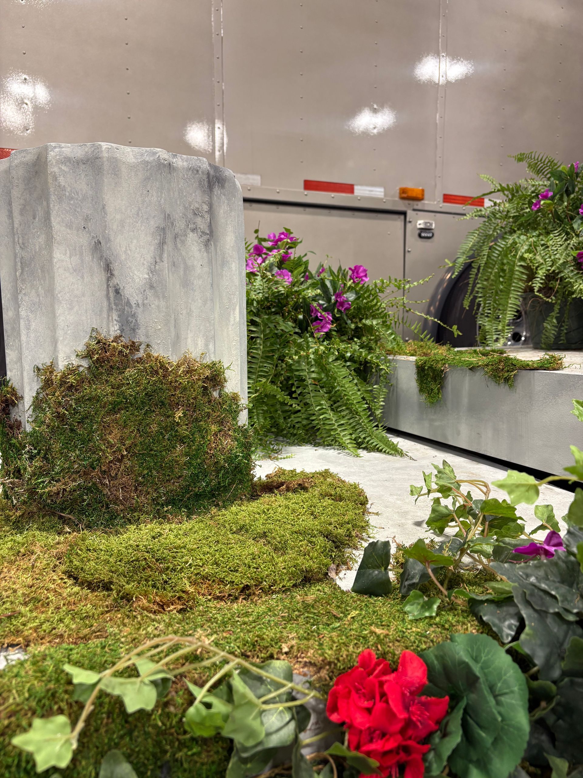 Faux garden with mossy columns and vibrant artificial flowers.