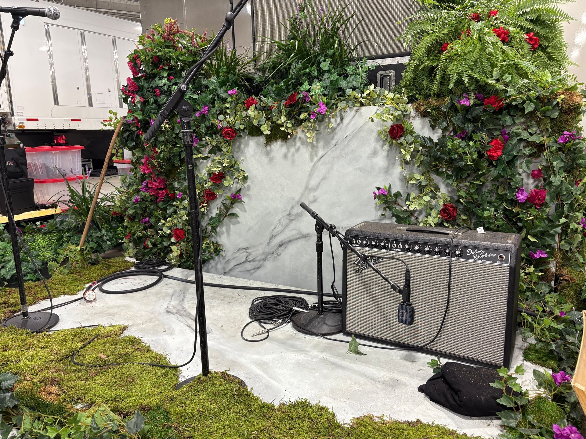 Stage with moss, flowers, amp, and microphone setup.