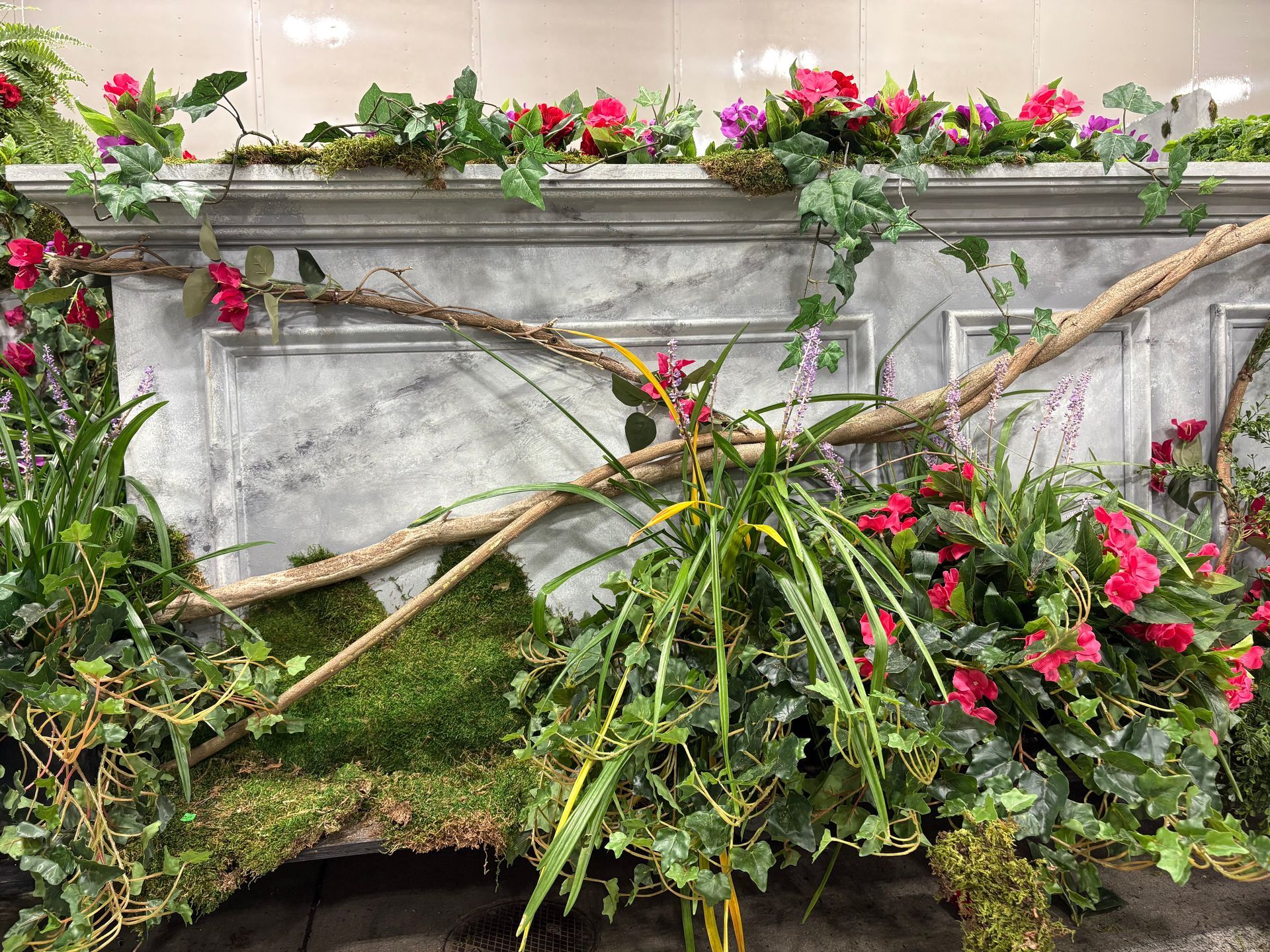 Floral display with red blooms, moss, and marble-patterned backdrop.
