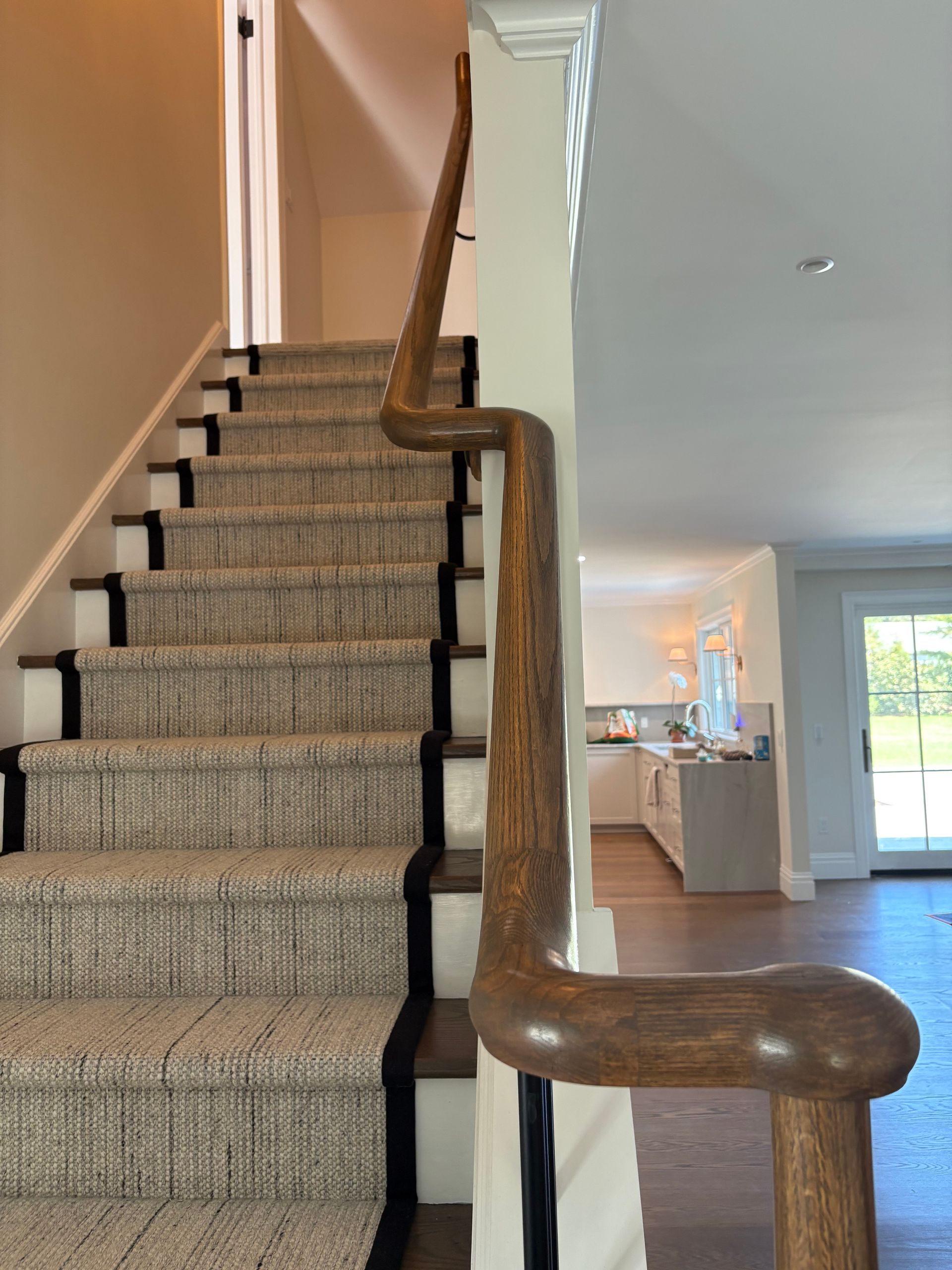 Staircase with beige runner, wood steps, and curved railing.
