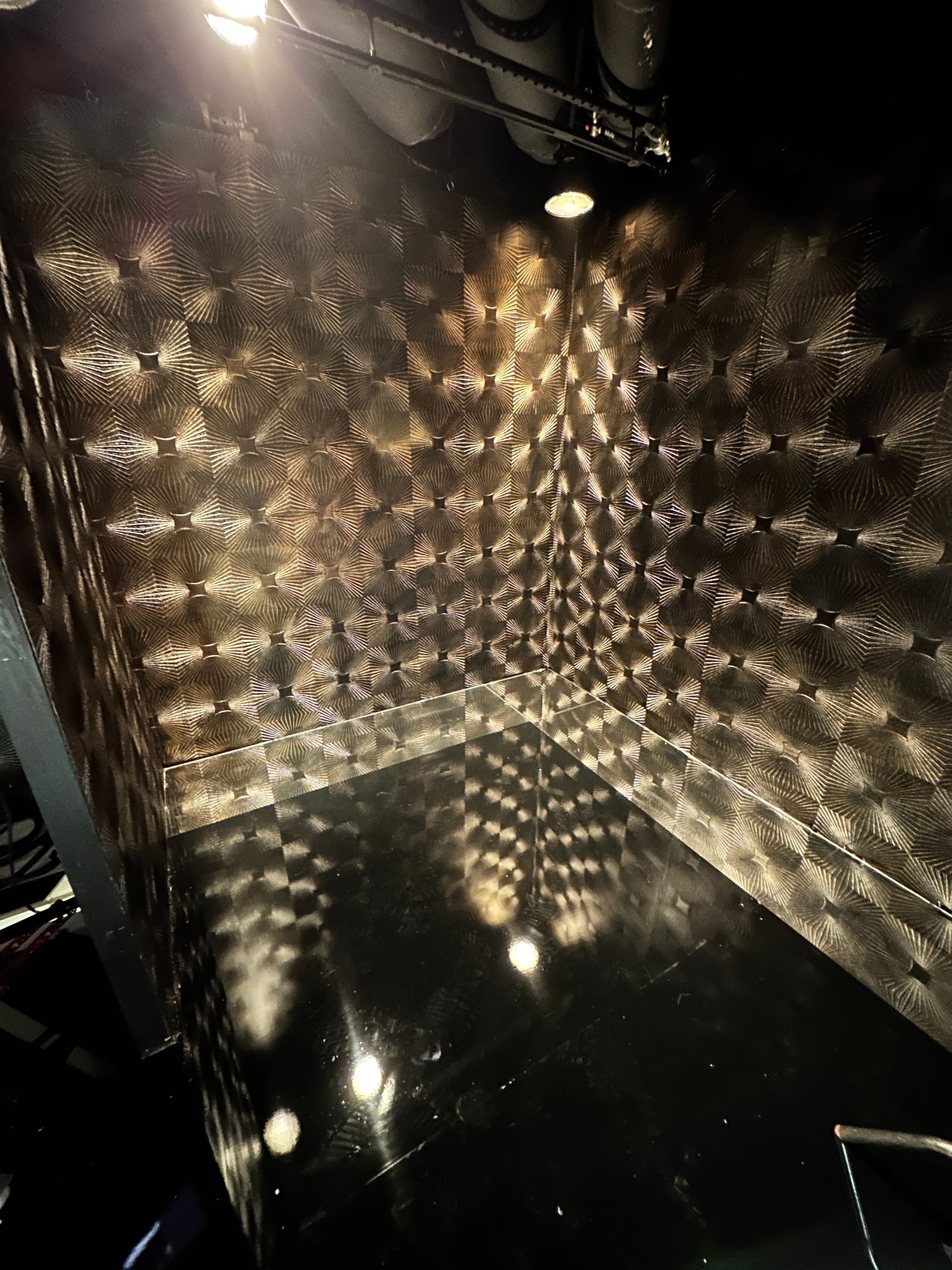 Reflective black mural with radial metallic wall texture.