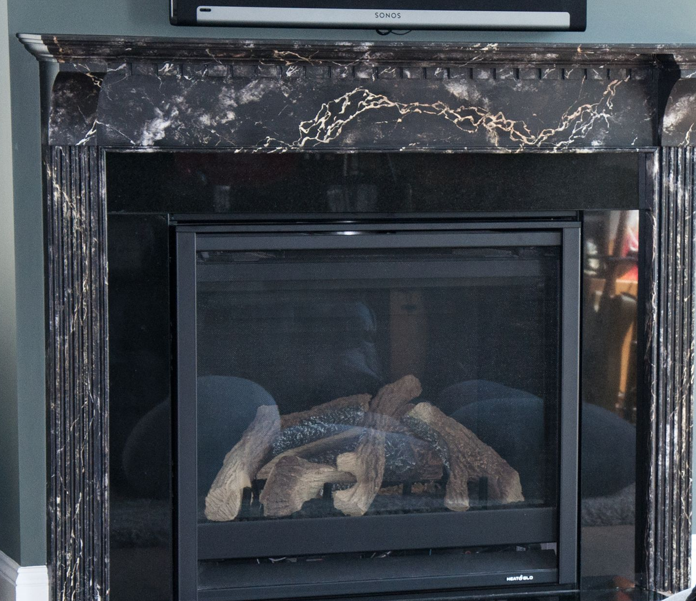 Fireplace with black marble, fluted columns, and soundbar.