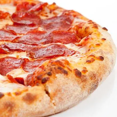A pepperoni pizza is sitting on a white surface.