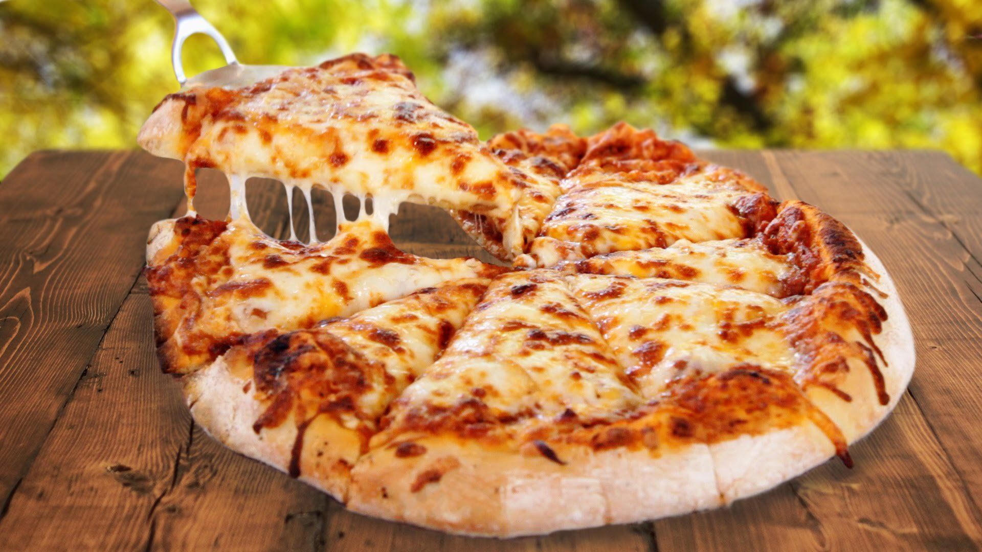 A pizza with a slice taken out of it is sitting on a wooden table.