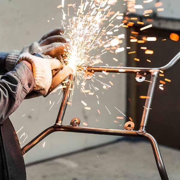 Person Grinding Metal Frame With Sparks Flying — Sheetmetal Improvements & Design in Molendinar, QLD