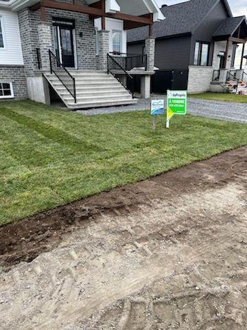 Cour avant nouvellement gazonnée avec maison, marches et panneaux « À vendre ».