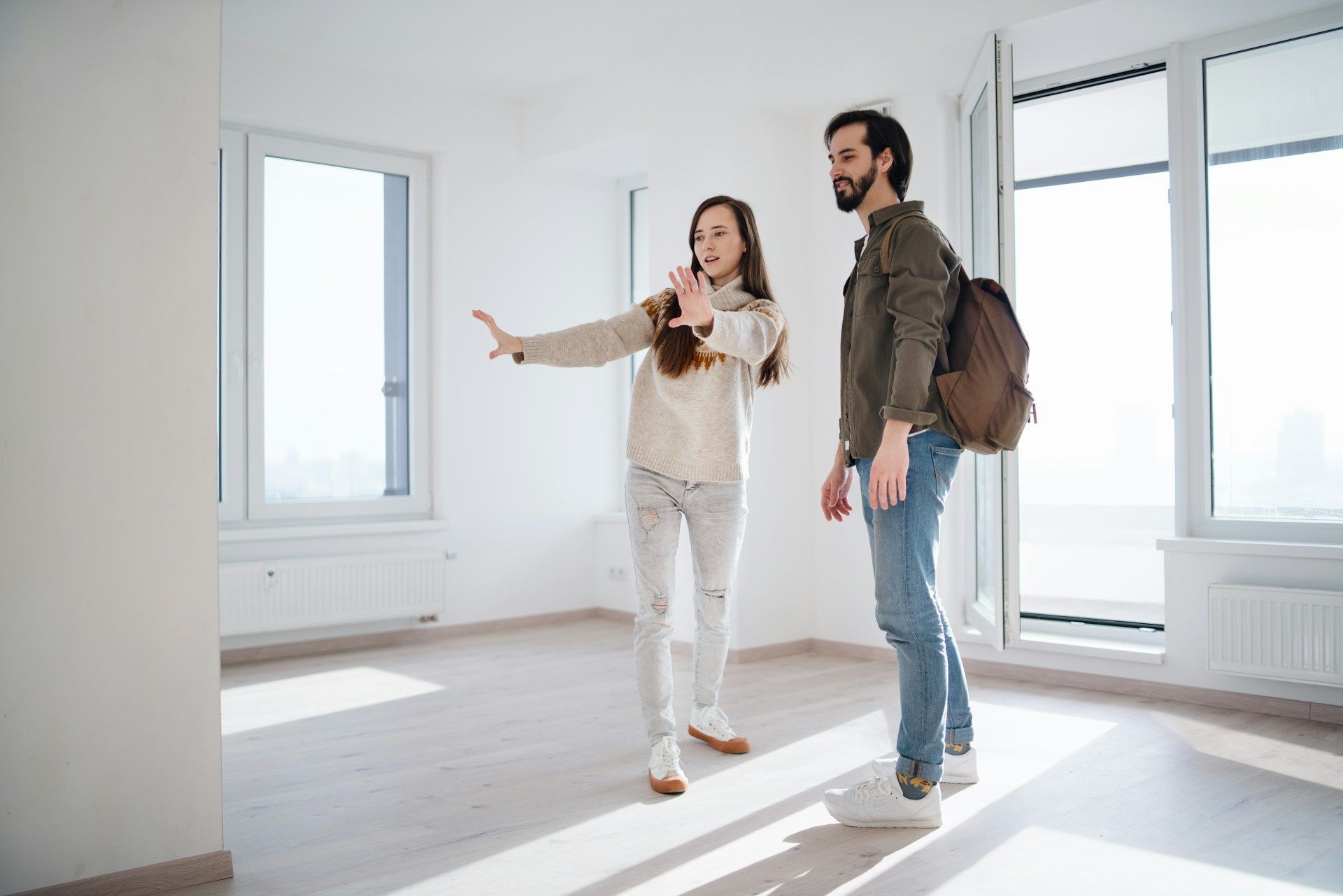 Person pointing, showing an empty room to another person.