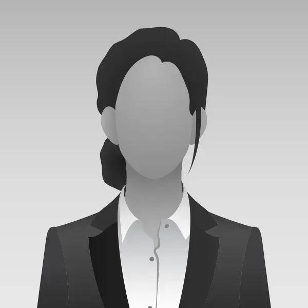 Woman in a blazer and collared shirt. Her hair is pulled back, with a gray gradient background.