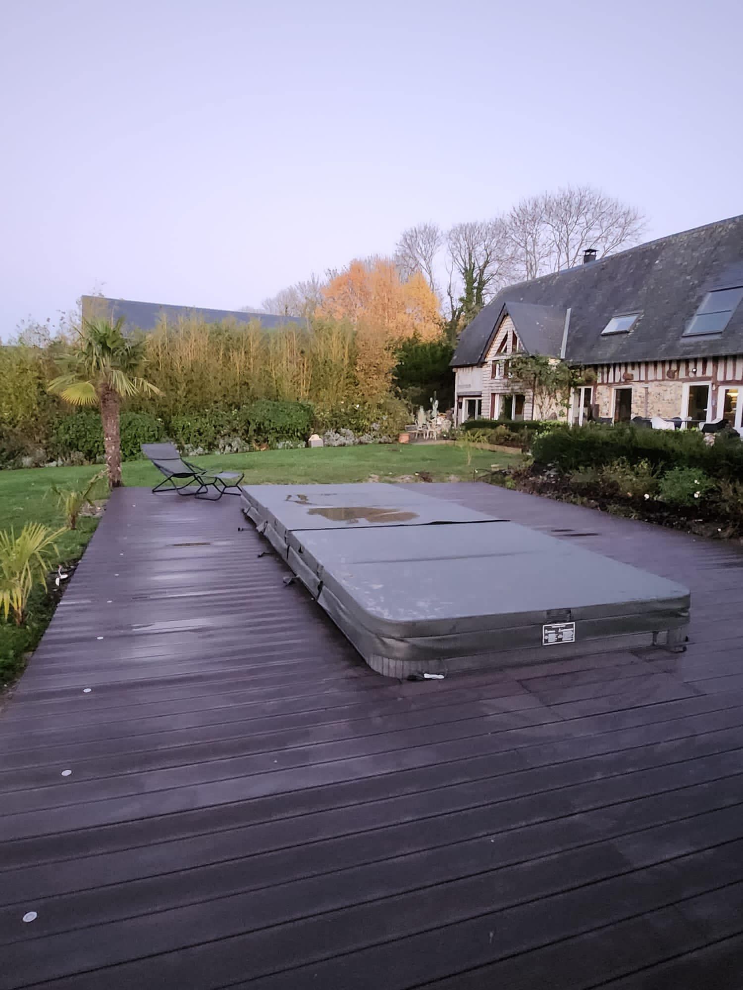 Terrasse en bois jouxtant une maison avec un abri de jacuzzi surélevé et un jardin au crépuscule