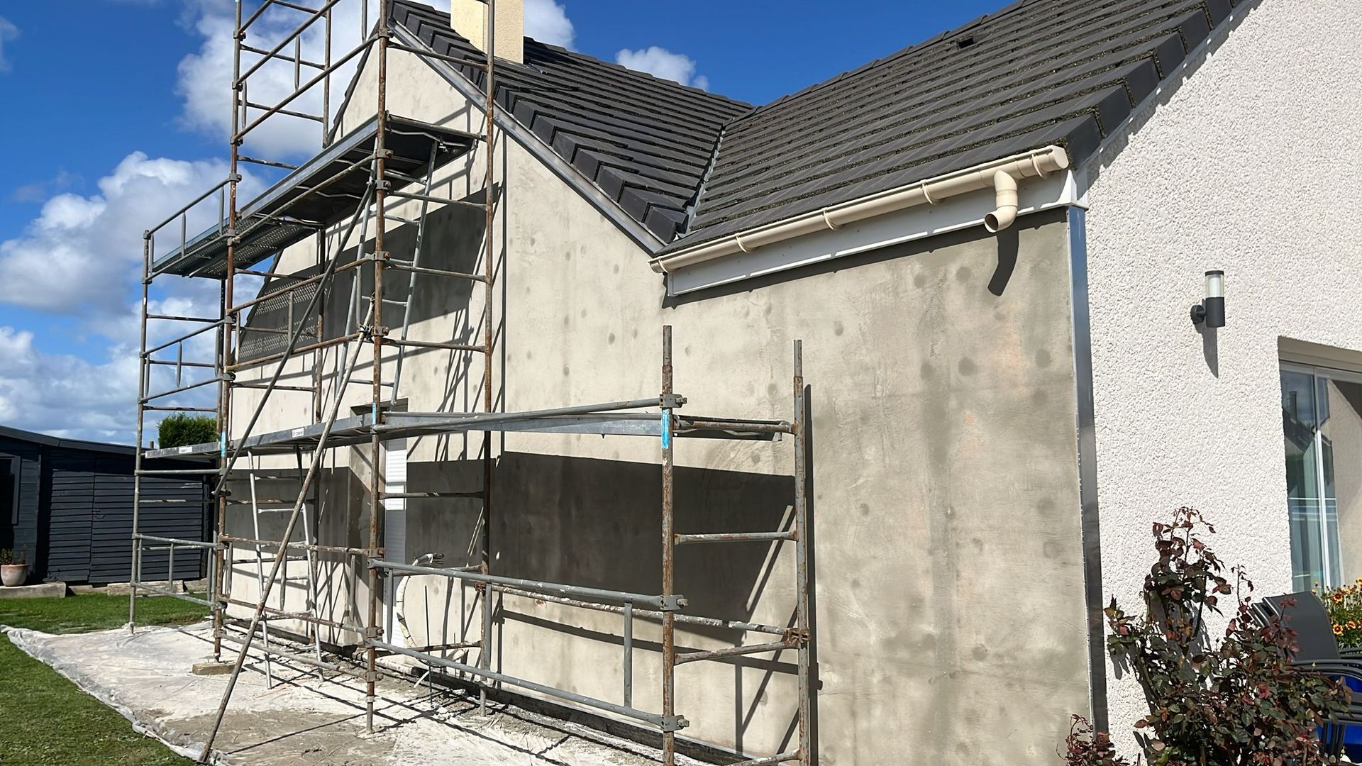 Extérieur d'une maison avec des échafaudages en cours de rénovation par une journée ensoleillée