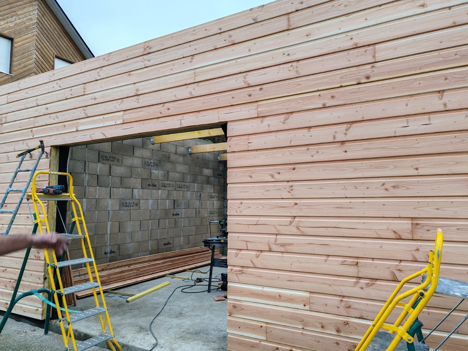 Mur extérieur en bois en construction avec échelles et une grande ouverture de porte