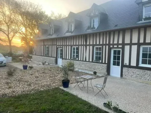 Une maison à colombages en briques, avec un toit gris, des fenêtres blanches et une pelouse verte devant.