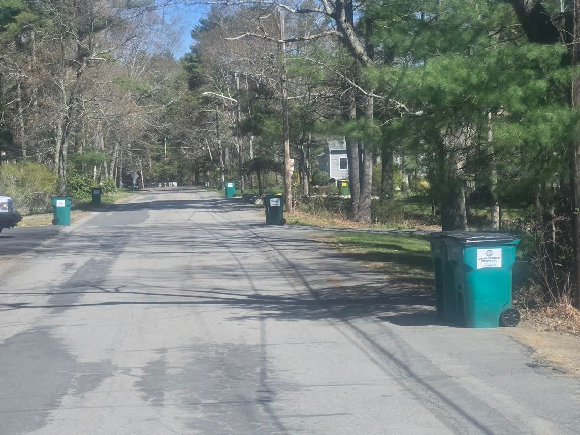 Bright green recycling bin between gray metal containers, with white trash visible inside.