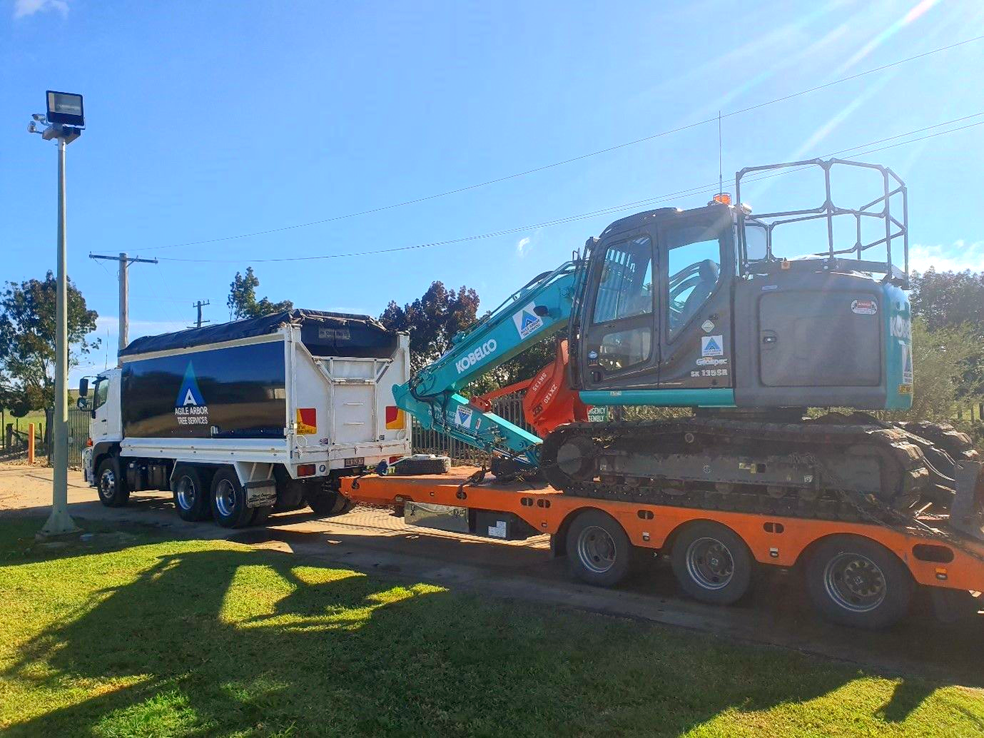 A Truck Pulling a Flatbed Trailer With an Excavator on It — Agile Arbor Pty Limited in Lithgow, NSW