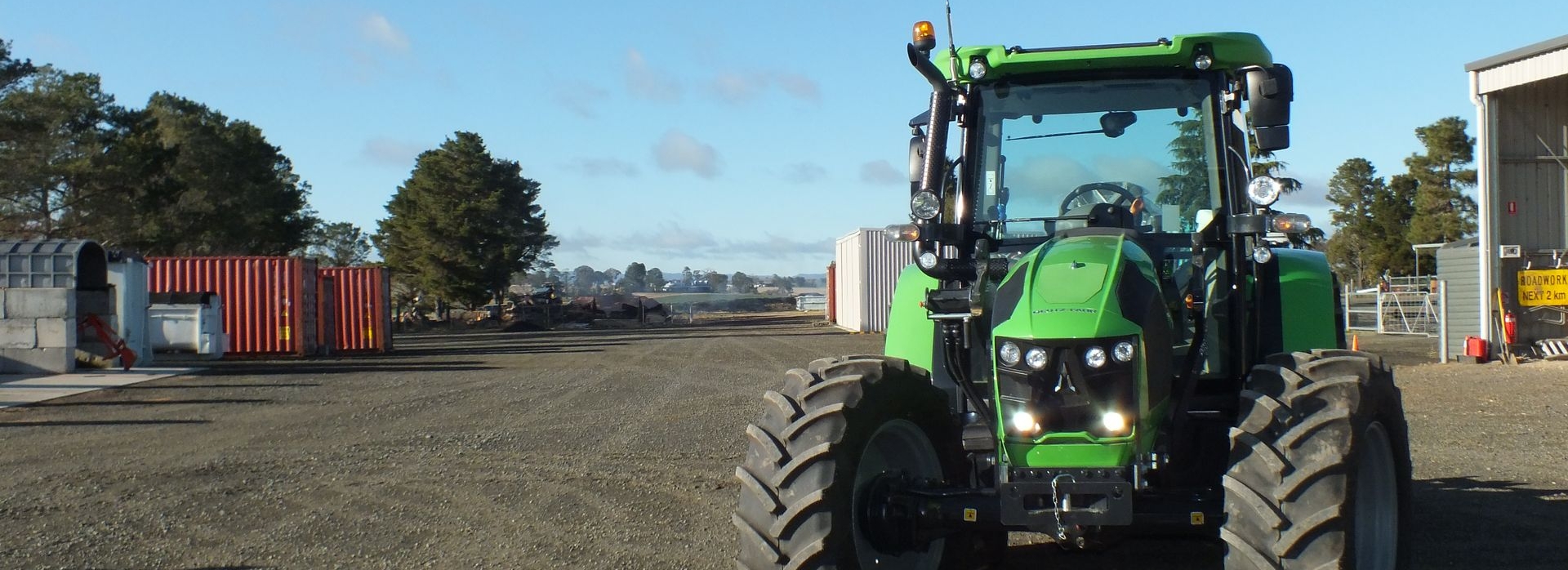 Green tractor parked on gravel road — Agile Arbor Pty Limited in Blue Mountains, NSW