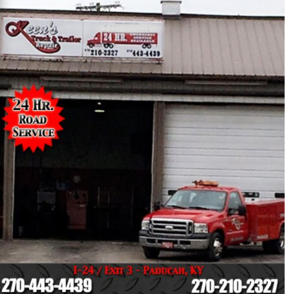 A red truck is parked in front of a building that says 24 hr road service
