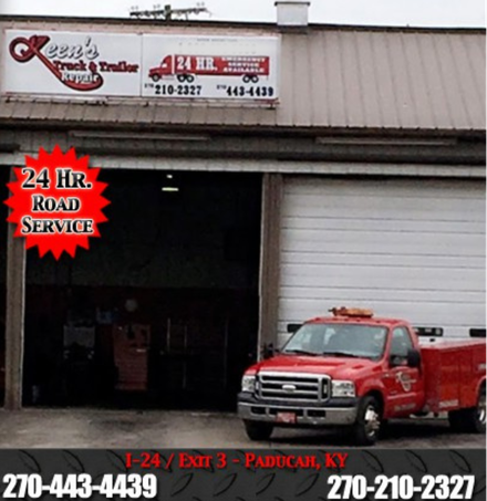 A red truck is parked in front of a building that says 24 hr road service