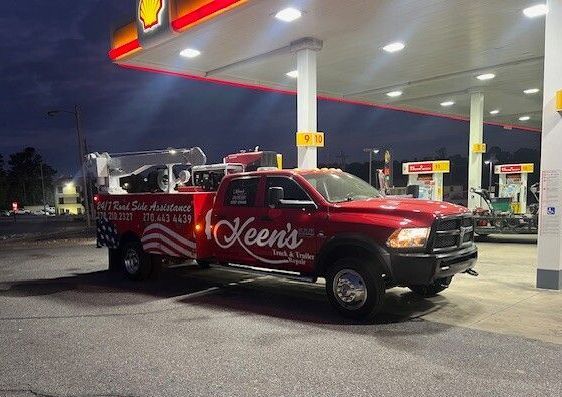 A red tow truck is parked in a gas station at night.