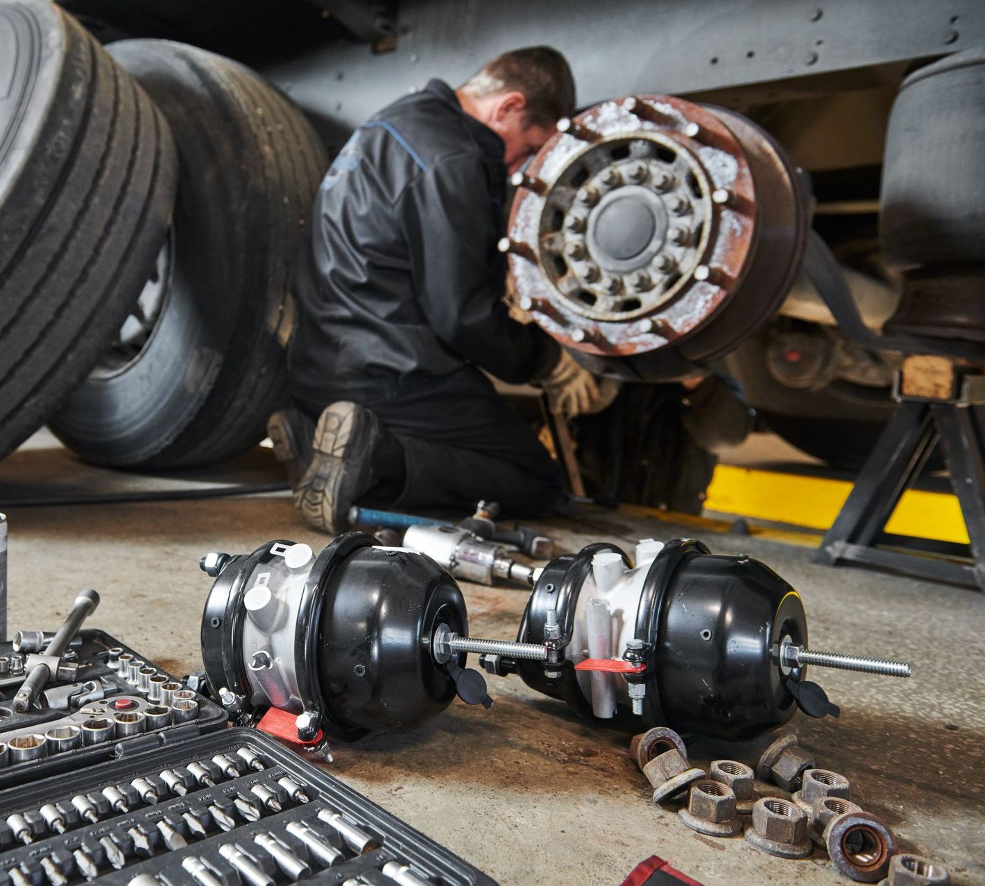 A man is kneeling down working on a truck