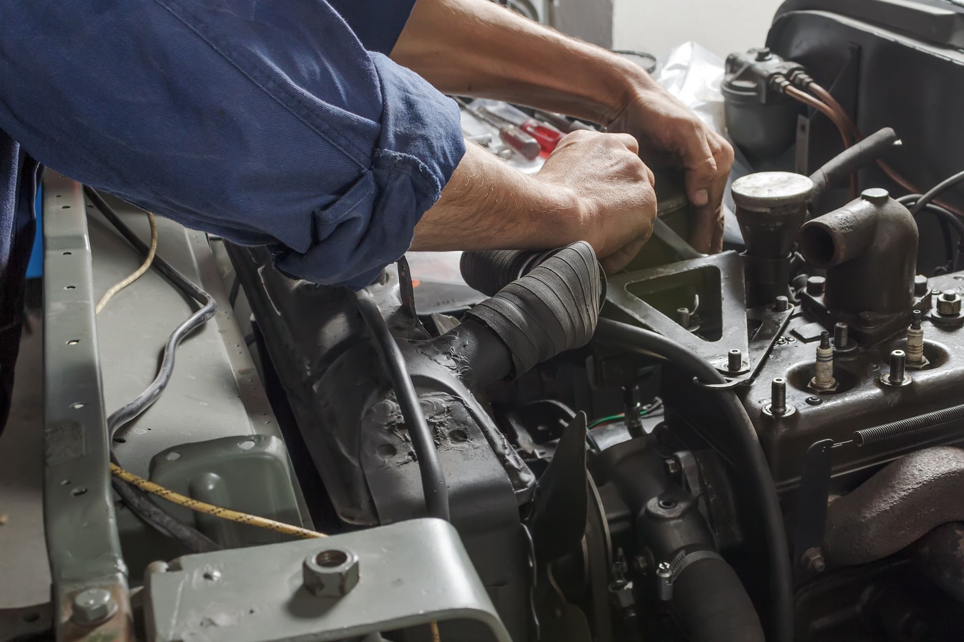 A man in a blue shirt is working on a car engine