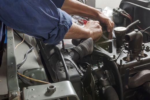 A man in a blue shirt is working on a car engine