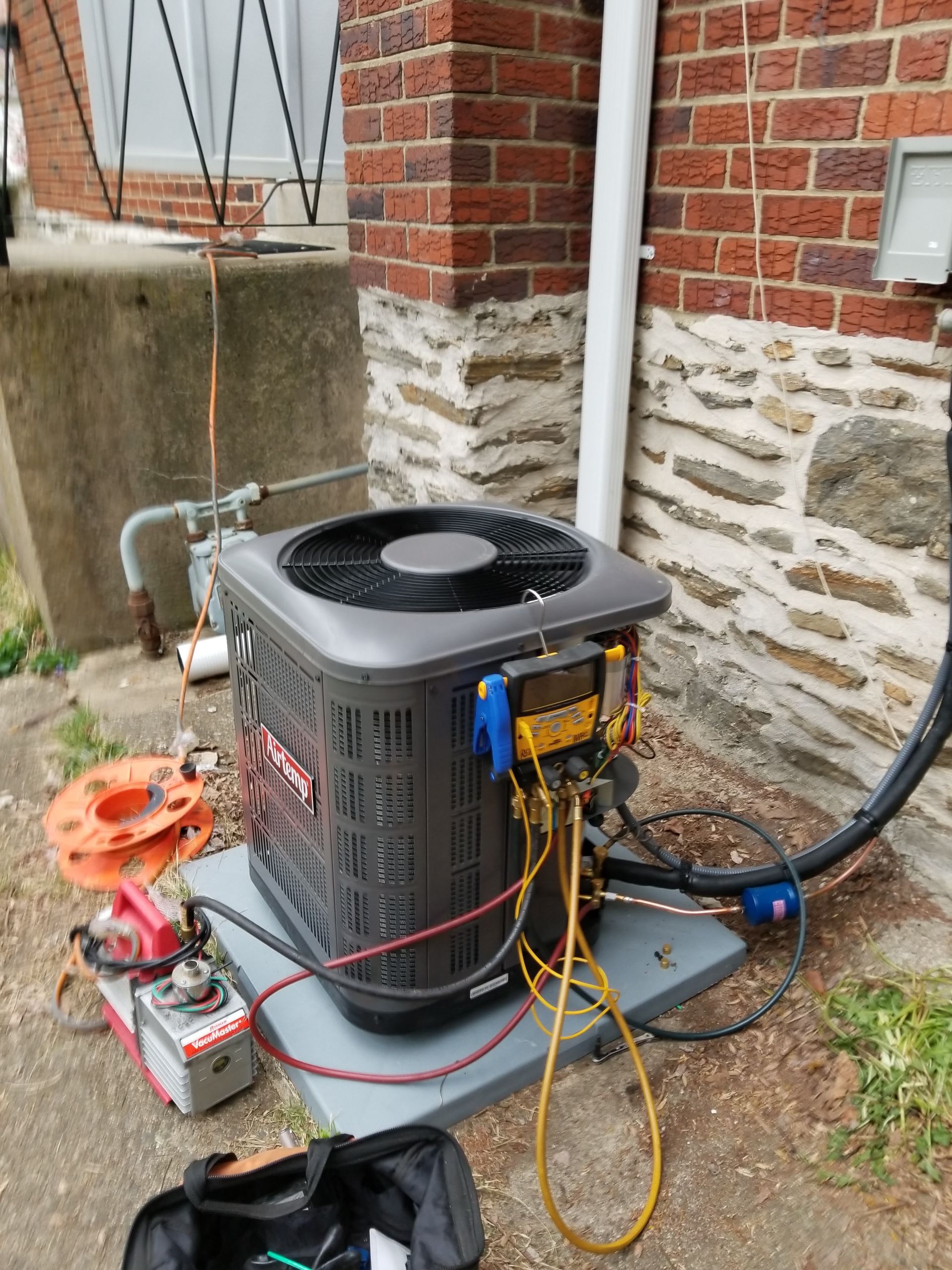 An air conditioner is being tested outside of a brick building.