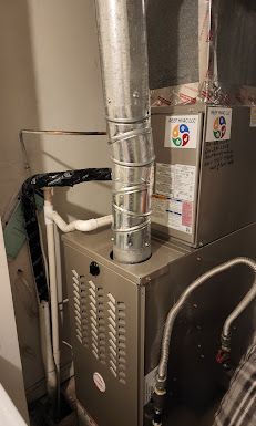 A furnace is sitting in a room next to a pipe.