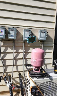A pink tank is sitting on top of an air conditioner outside of a house.