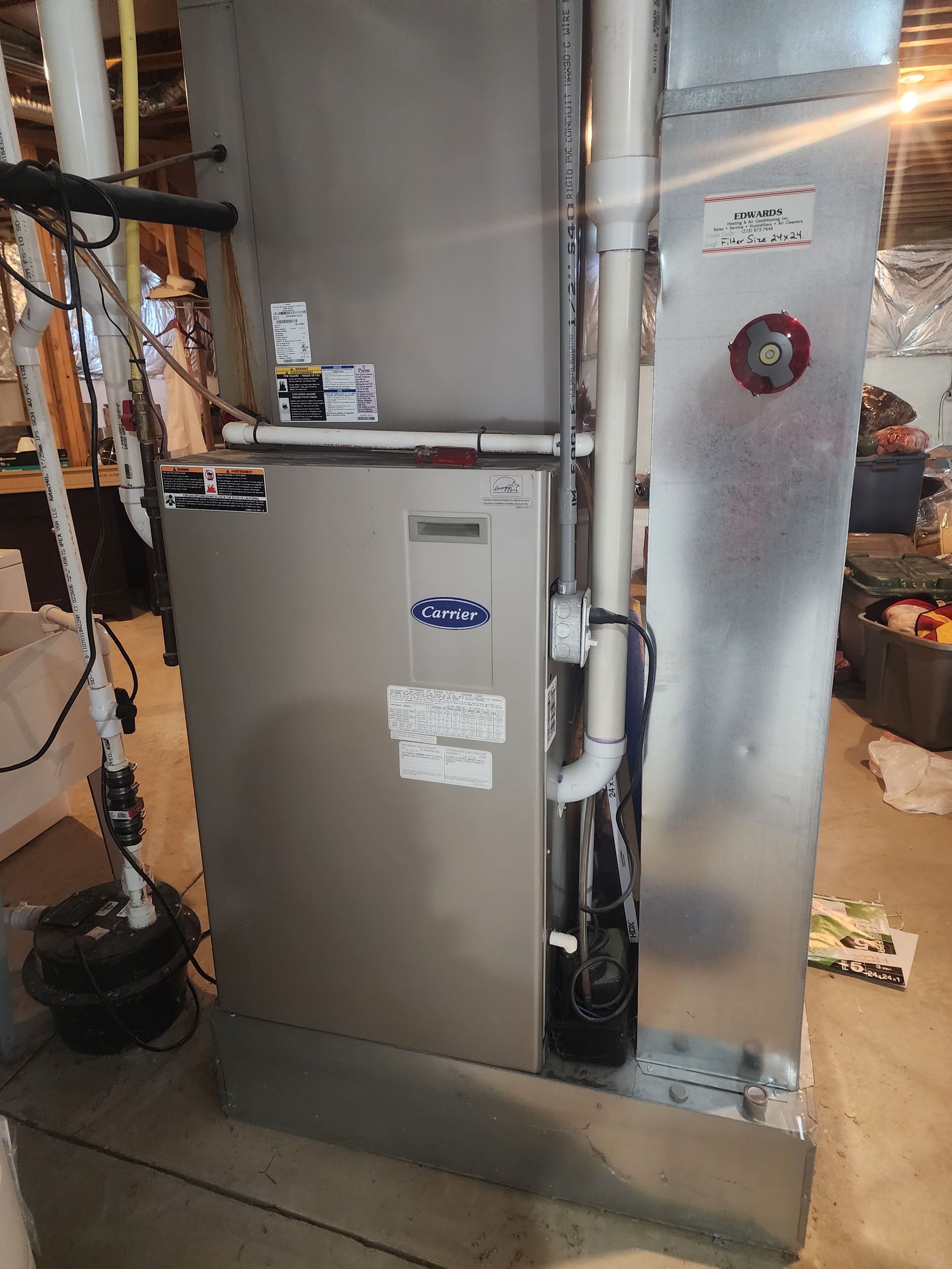 A silver air conditioner is sitting in a basement.
