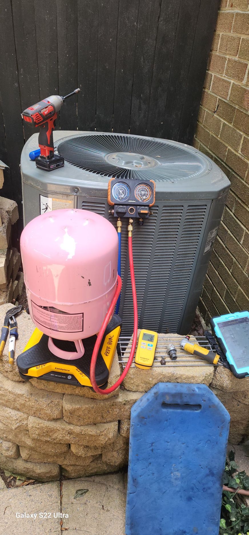 A pink cylinder is sitting next to an air conditioner.