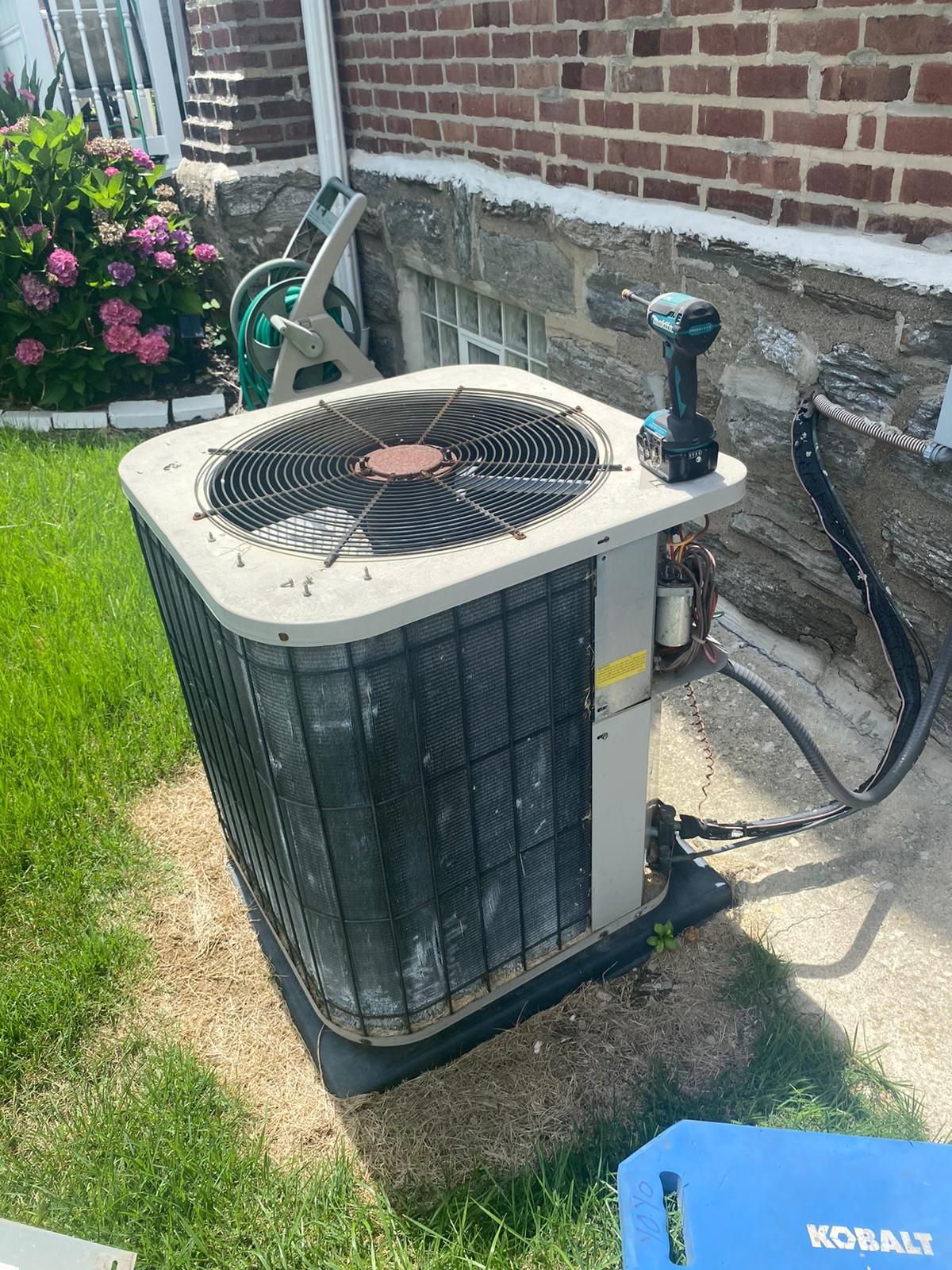 An air conditioner is sitting on the side of a brick building.