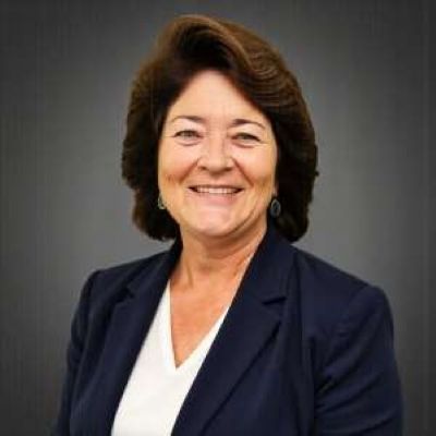 A woman in a blue jacket and white shirt is smiling for the camera.