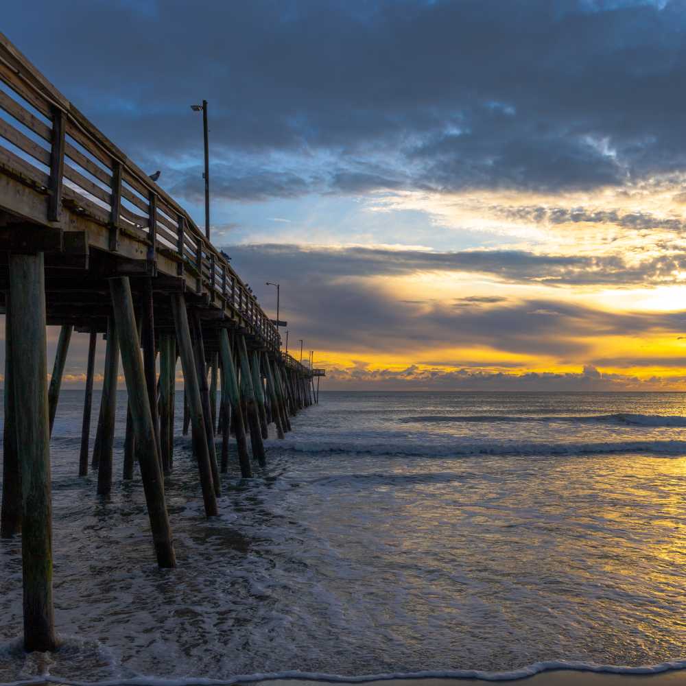 A pier leading into the ocean at sunset