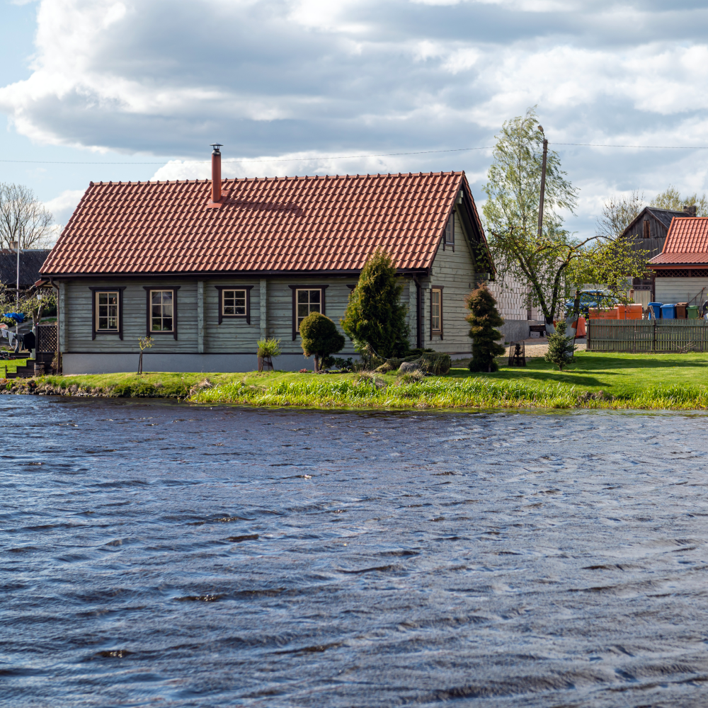 A house with a red tile roof sits next to a body of water