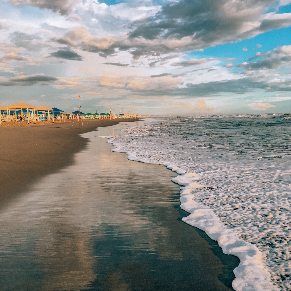 A beach with a lot of umbrellas and waves coming in