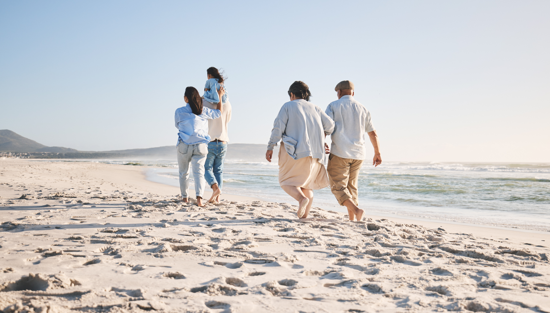 A group of people are walking on the beach.