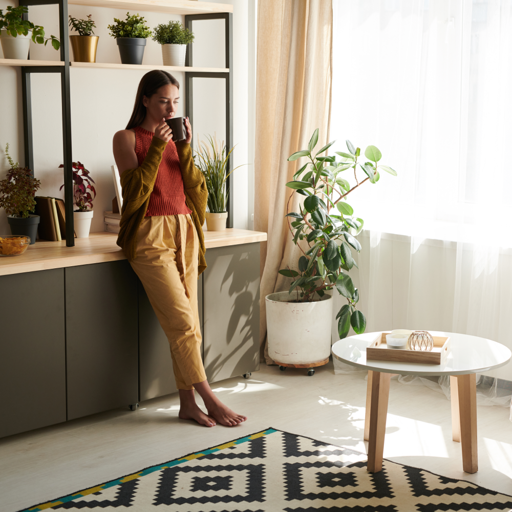 A woman is drinking a cup of coffee in a living room.