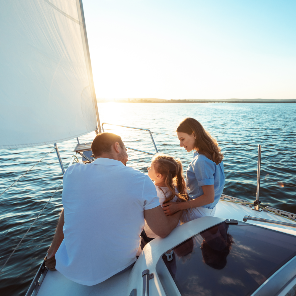 A family is sitting on a sailboat in the water.
