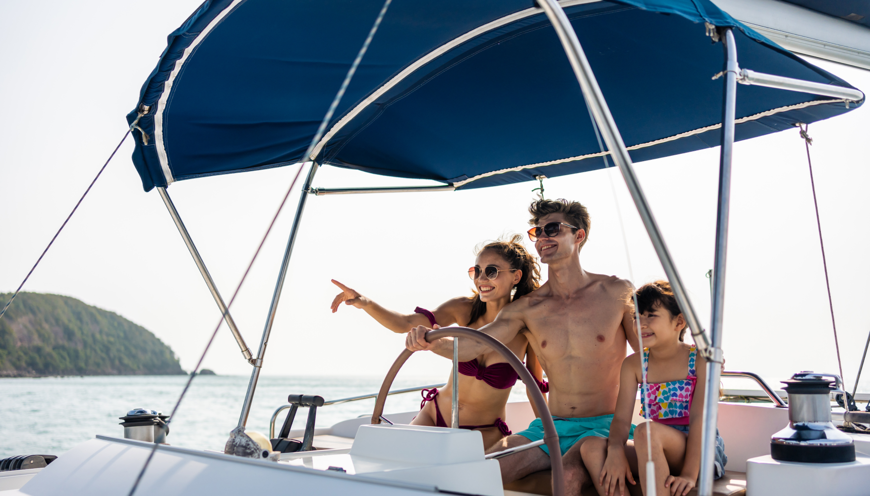 A family is sitting on a sailboat in the ocean.