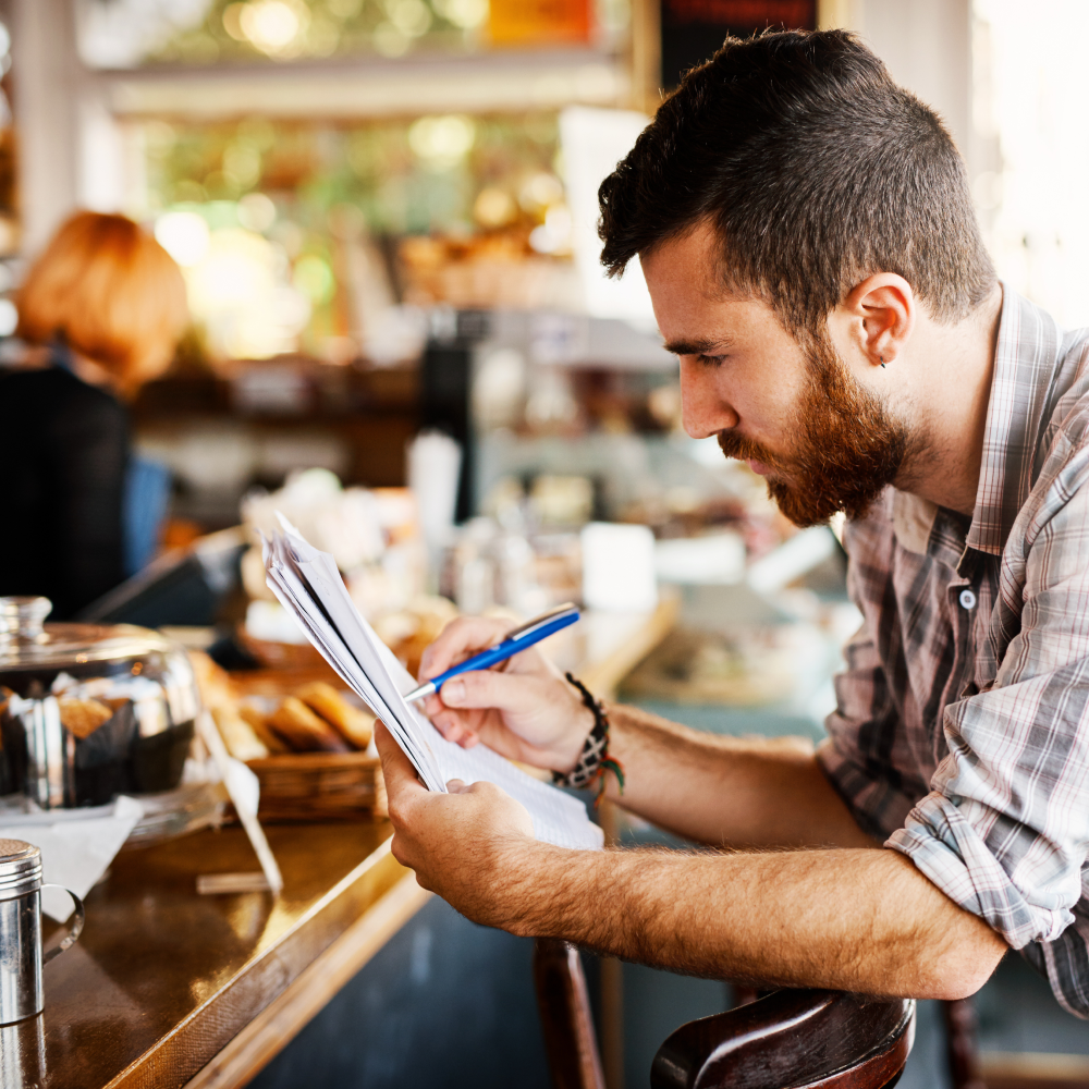 A man is sitting at a bar writing on a piece of paper