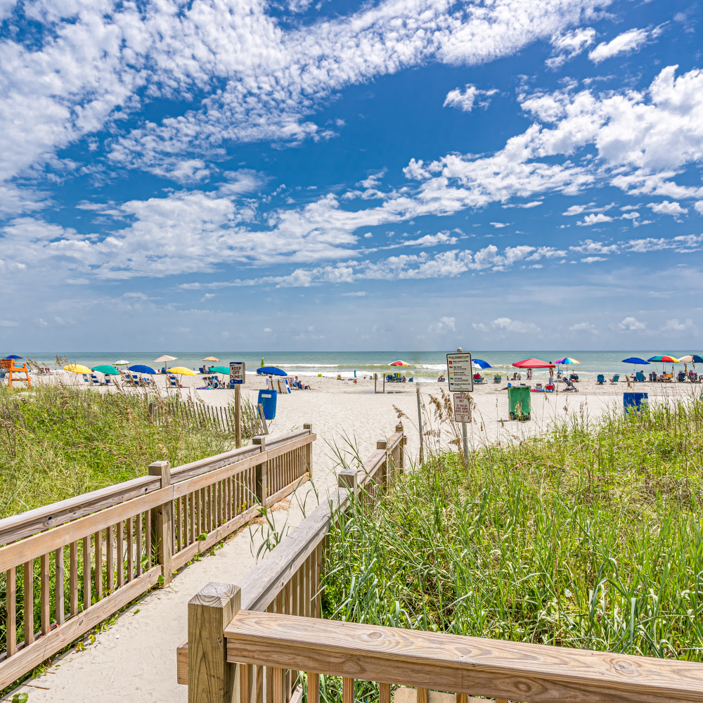 A wooden walkway leading to the beach on a sunny day