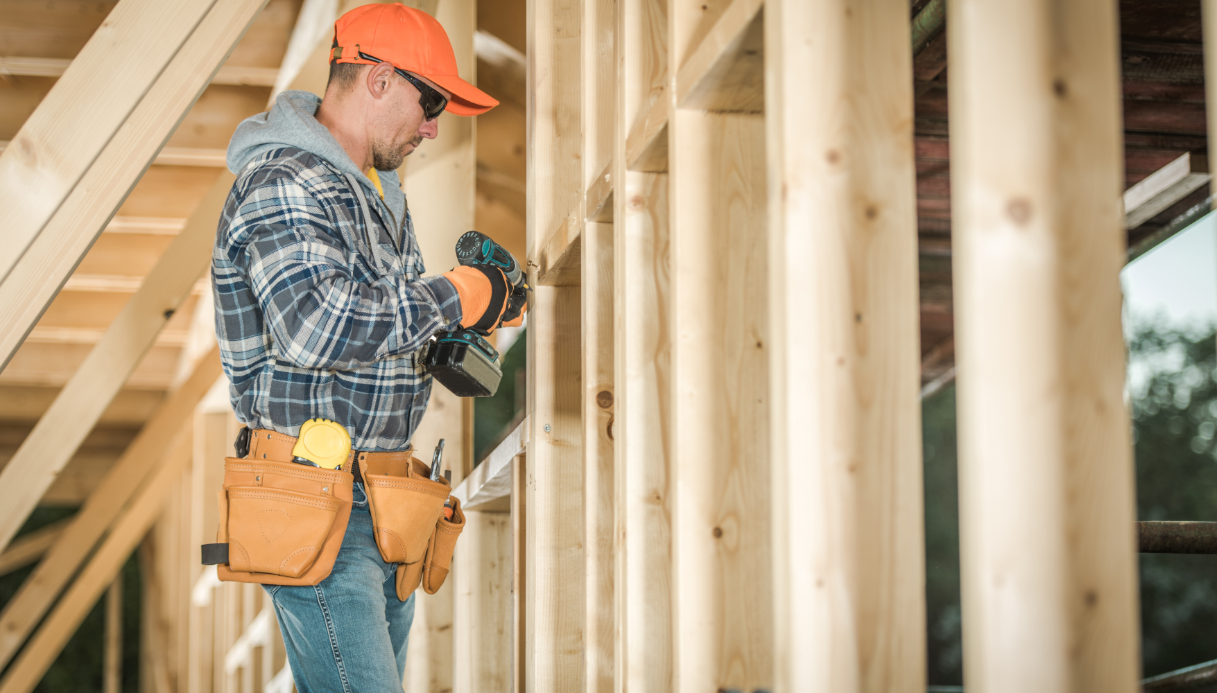 A construction worker is working on a wooden frame of a house.