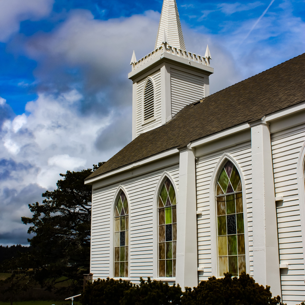 A white church with a steeple and stained glass windows