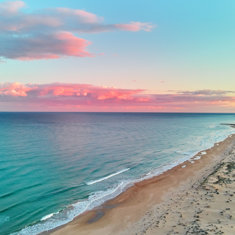 An aerial view of a beach with a sunset in the background.