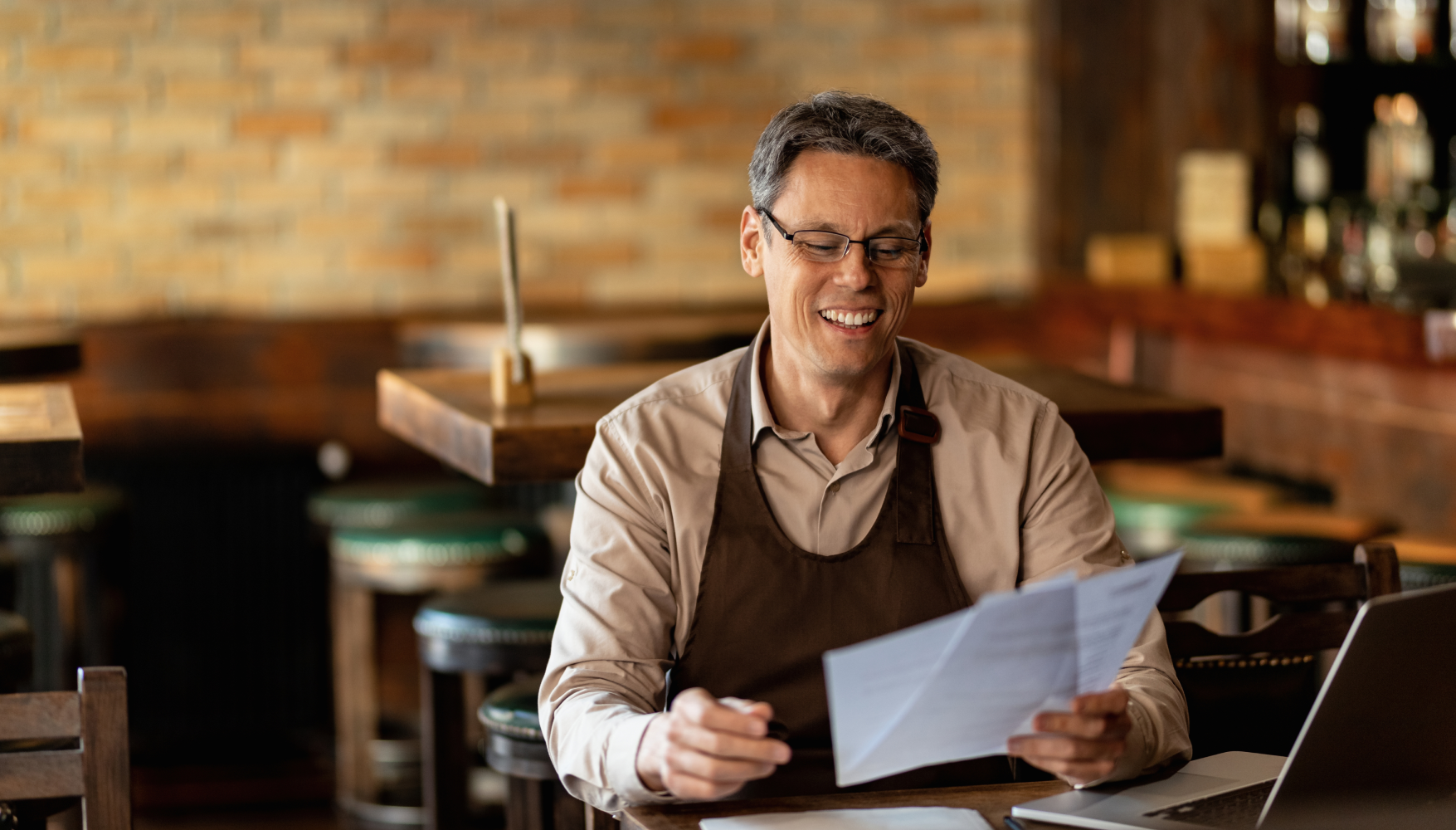 A man is sitting at a table in a restaurant looking at a piece of paper.