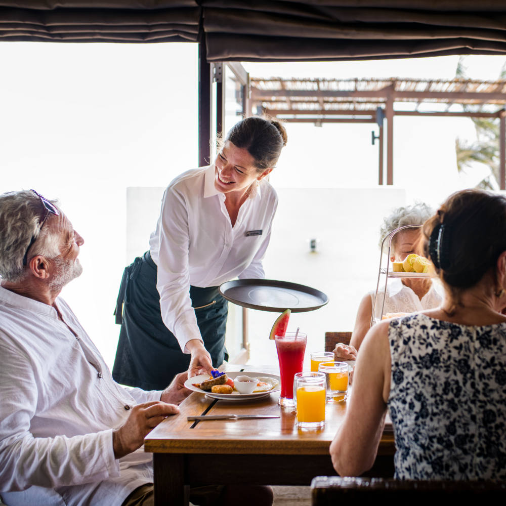 A woman is serving food to a group of people at a table