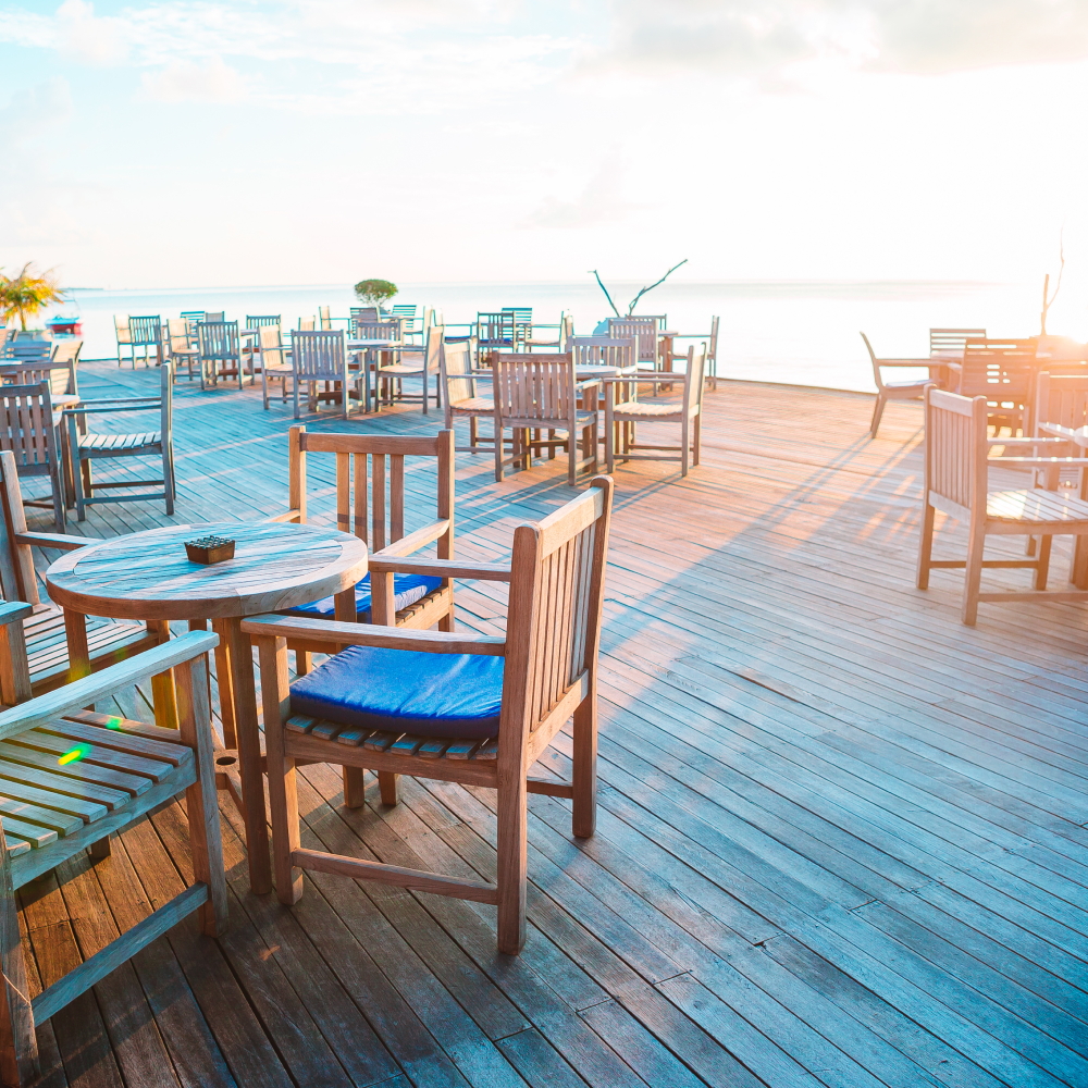 Tables and chairs on a wooden deck overlooking the ocean