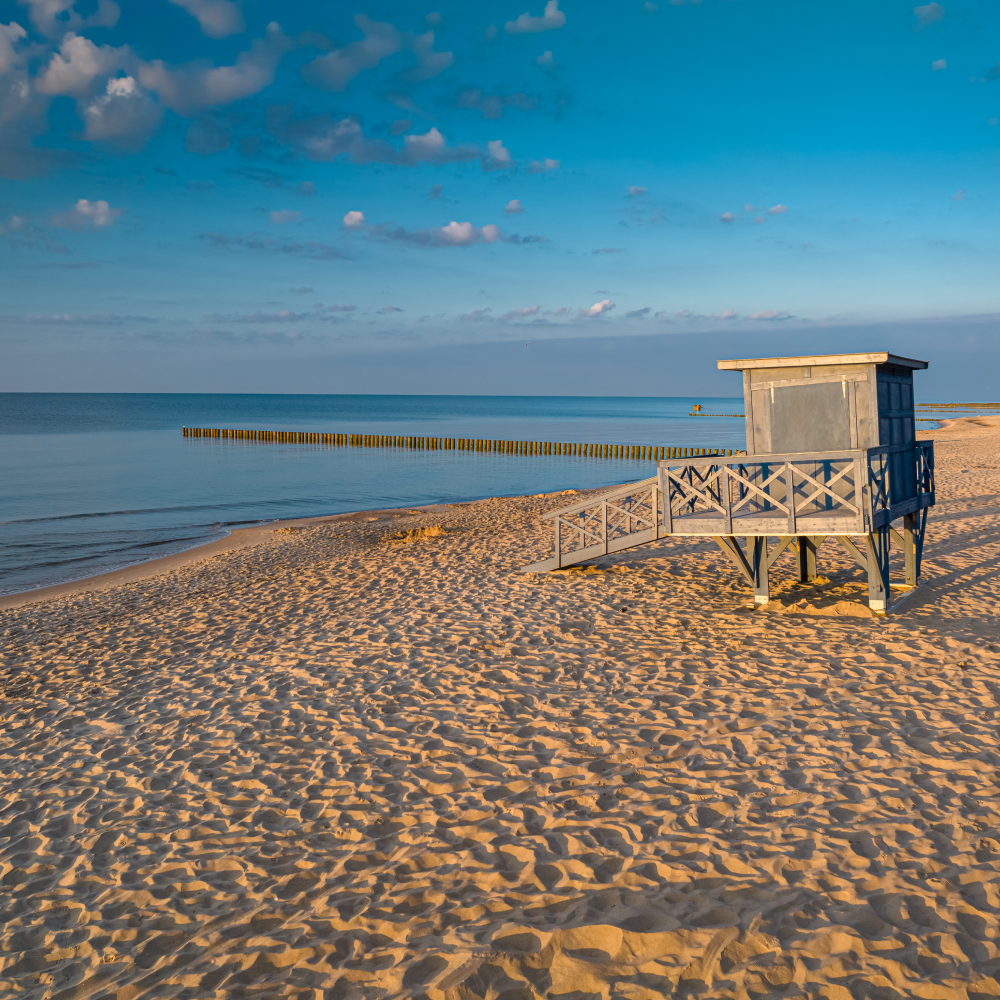 A lifeguard tower is sitting on a sandy beach near the ocean.