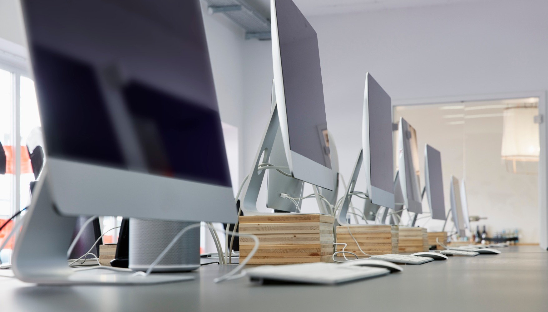 A row of computer monitors are lined up on a table.