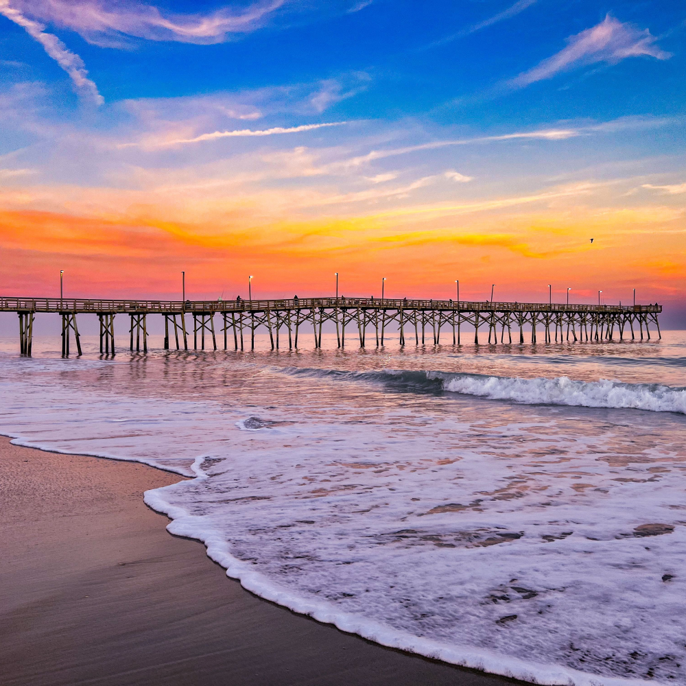 A pier leading into the ocean at sunset